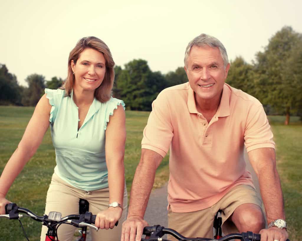 joyous middle aged couple riding bikes.