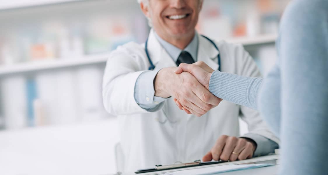 primary care doctor and patient shaking hands.