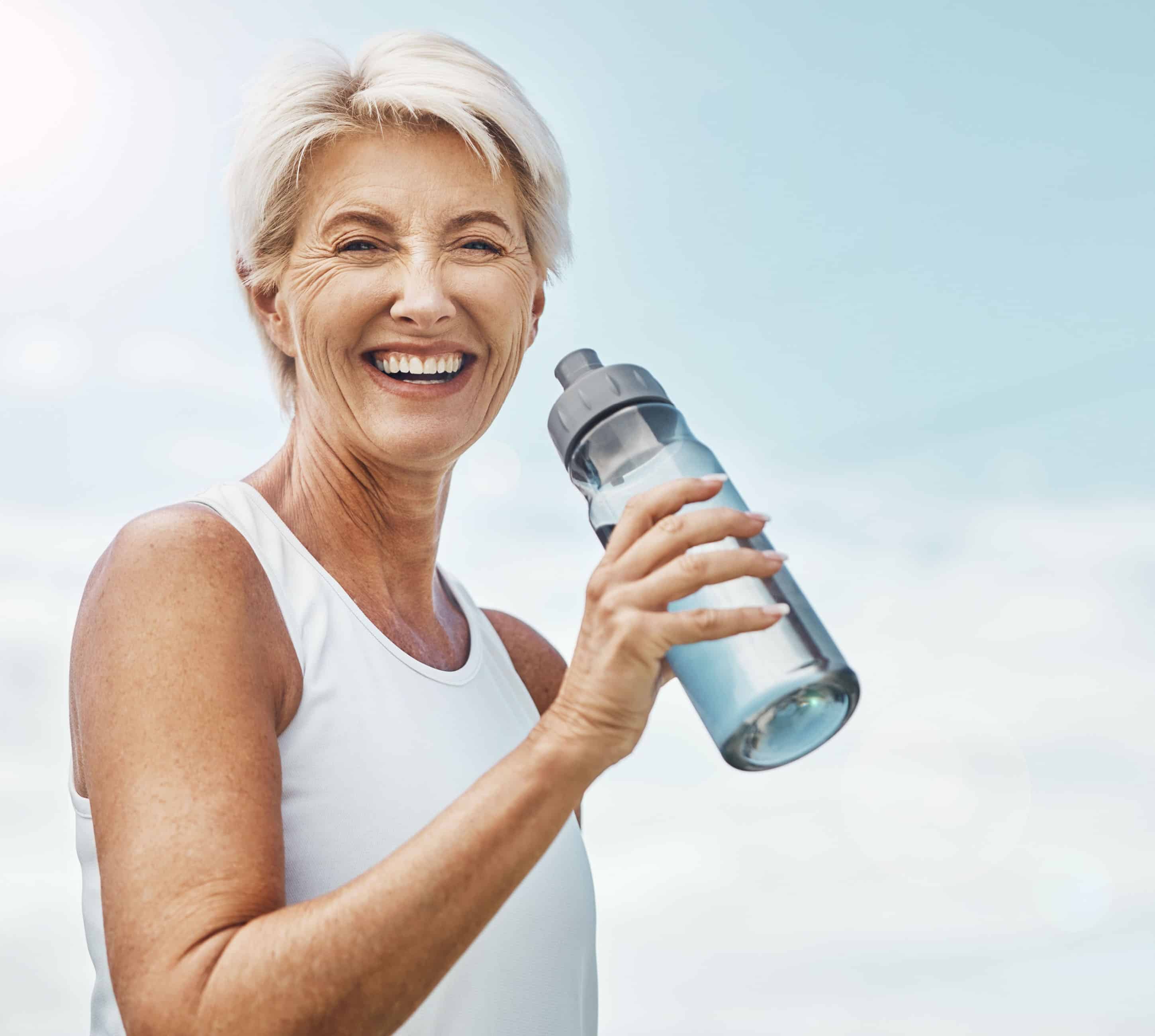 vibrant senior woman drinking from water bottle.